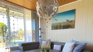 A modern living room with a wooden ceiling, a large window, a sofa, a coffee table, and a painting on the wall. - Freistehendes Ferienhaus in Tossens mit Terrasse by Interhome (Burhave)