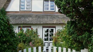 A traditional house with a thatched roof, white exterior walls, and a white picket fence. - Geltinger Birk by Interhome (Gelting)