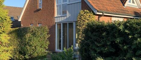Ein zweistöckiges Haus mit Schrägdach, Ziegelaußenwand und einem großen Fenster.