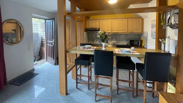 Una cocina compacta con armarios de madera, una isla central con taburetes de bar y una pequeña mesa de comedor.