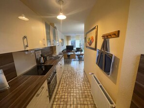 Una cocina moderna con una isla central, un comedor con televisor y un pasillo que conduce a una sala de estar.