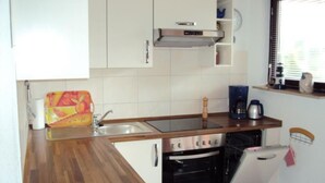 A compact kitchen with a wooden countertop, a built-in oven, a sink, and white cabinets. - Pratzat by Interhome (Büsum)