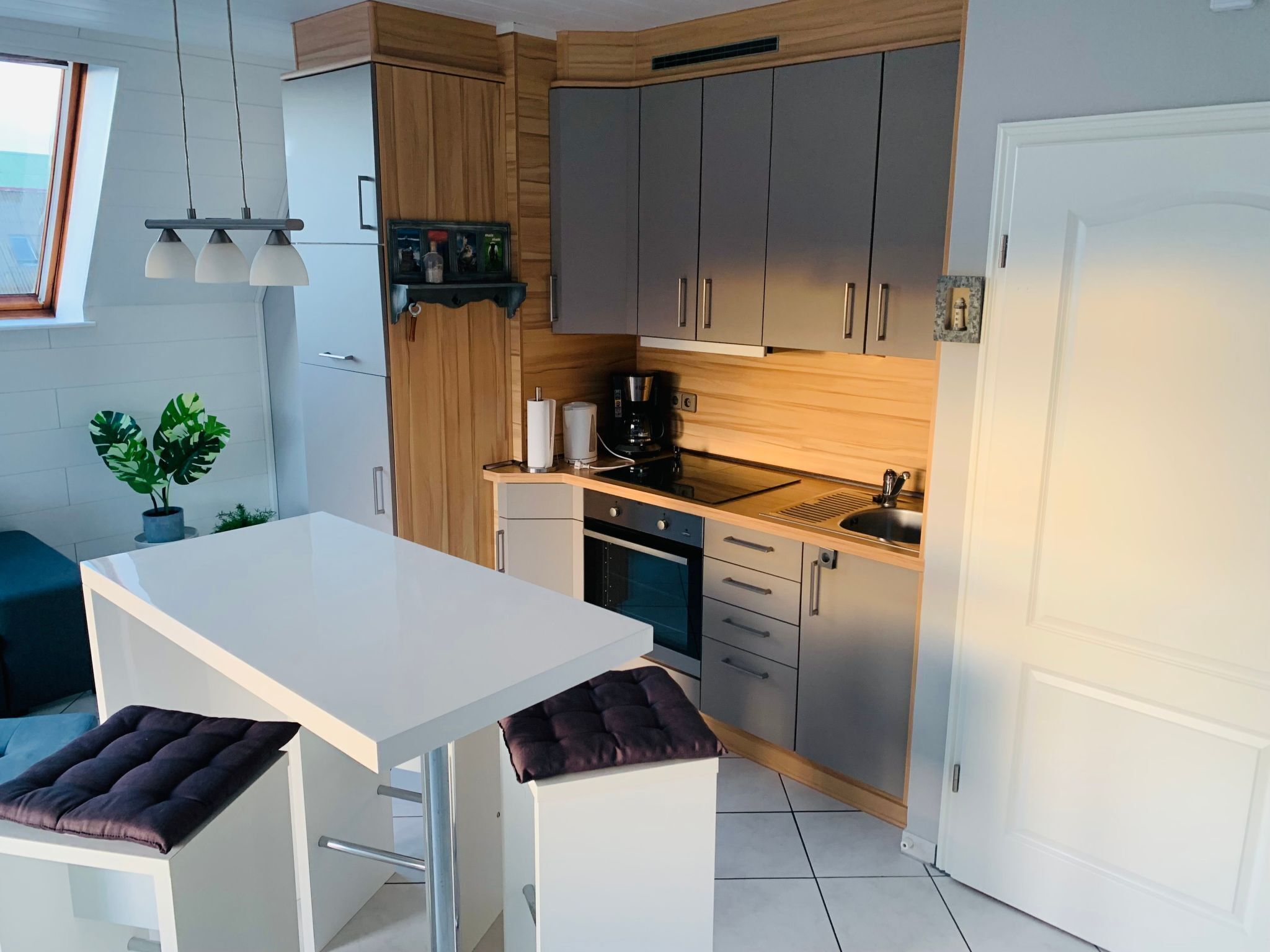 A compact kitchen with a white countertop, stainless steel appliances, and wooden cabinets.