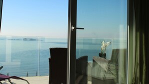 A balcony with a glass door, a chair, a small table with a plant, and a view of the sea. - Gemütliche Ferienwohnung in Mlini mit Großer Terrasse by Interhome (Dubrovnik/Mlini)
