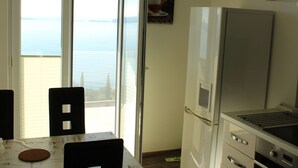 A kitchen with a view of the sea, a refrigerator, and a dining area with a table and chairs. - Gemütliche Ferienwohnung in Mlini mit Großer Terrasse by Interhome (Dubrovnik/Mlini)