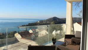A balcony with a clear view of the sea and hills, wicker furniture, and a potted orchid. - Gemütliche Ferienwohnung in Mlini mit Großer Terrasse by Interhome (Dubrovnik/Mlini)
