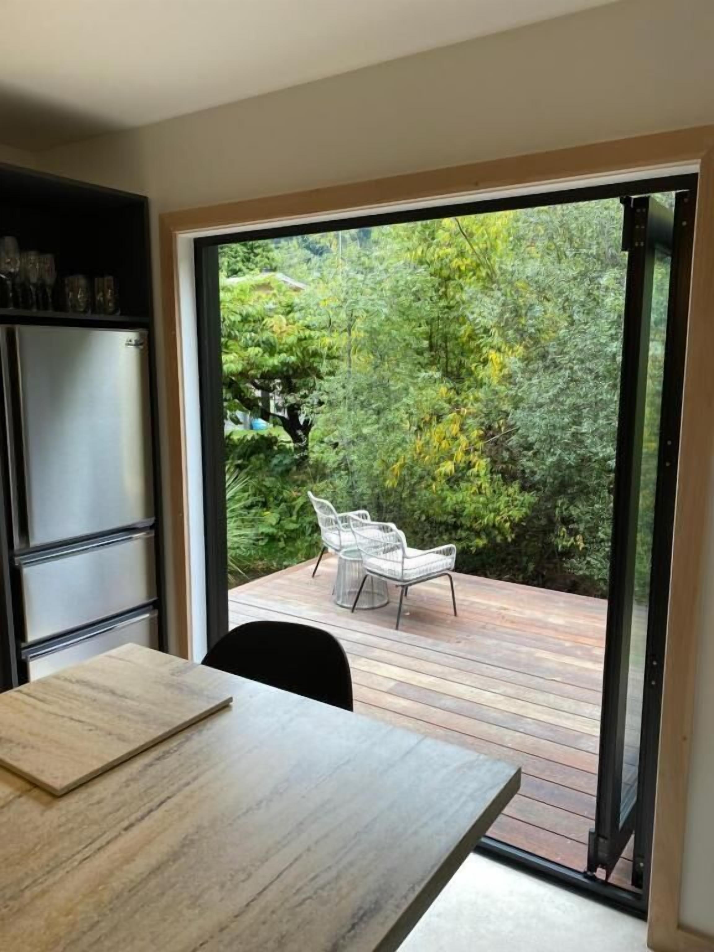 Una cuina moderna amb una porta corredissa de vidre que dona a una terrassa exterior amb cadires.
