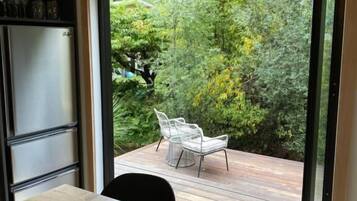 A modern kitchen with a sliding glass door leading to an outdoor deck with chairs.