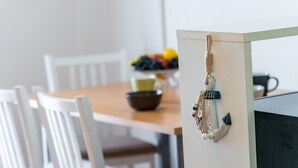 Ein Essbereich mit Holztisch, weißen Stühlen und einem dekorativen Anker an der Wand.