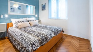 Ein Schlafzimmer mit Bett, Nachttisch, Spiegel und Fenster.