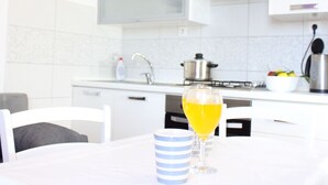 Eine moderne Küche mit weißen Schränken, einem Edelstahlherd und einer Spüle. Ein Tisch mit einem Glas Orangensaft und einer gestreiften Tasse.
