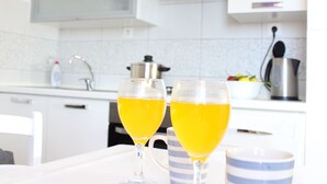 A modern kitchen with white cabinets, a stainless steel kettle, and two glasses of orange juice on a table. - "Slaven" mit Blick auf das Wasser by Interhome (Podgora)