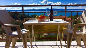 A table with a bowl of fruit, two wine glasses, and a bottle on a balcony overlooking a scenic view. - "Slaven" mit Blick auf das Wasser by Interhome (Podgora)