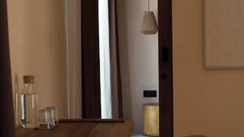 Un comedor con una mesa de madera, sillas, una lámpara colgante y una puerta que da a otra habitación.
