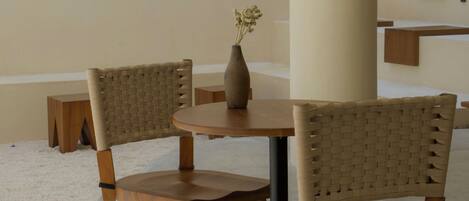 A modern interior with two wooden chairs, a round table, and a vase with flowers.