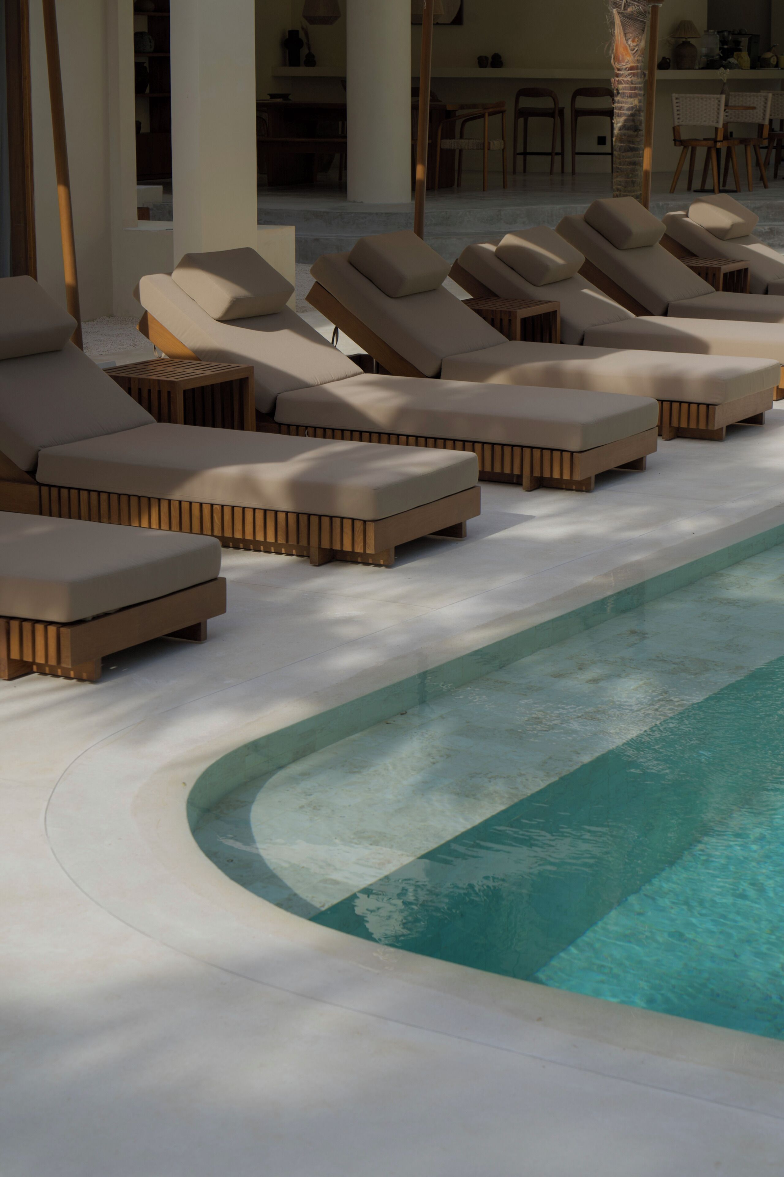 A poolside area with lounge chairs and a clear pool.