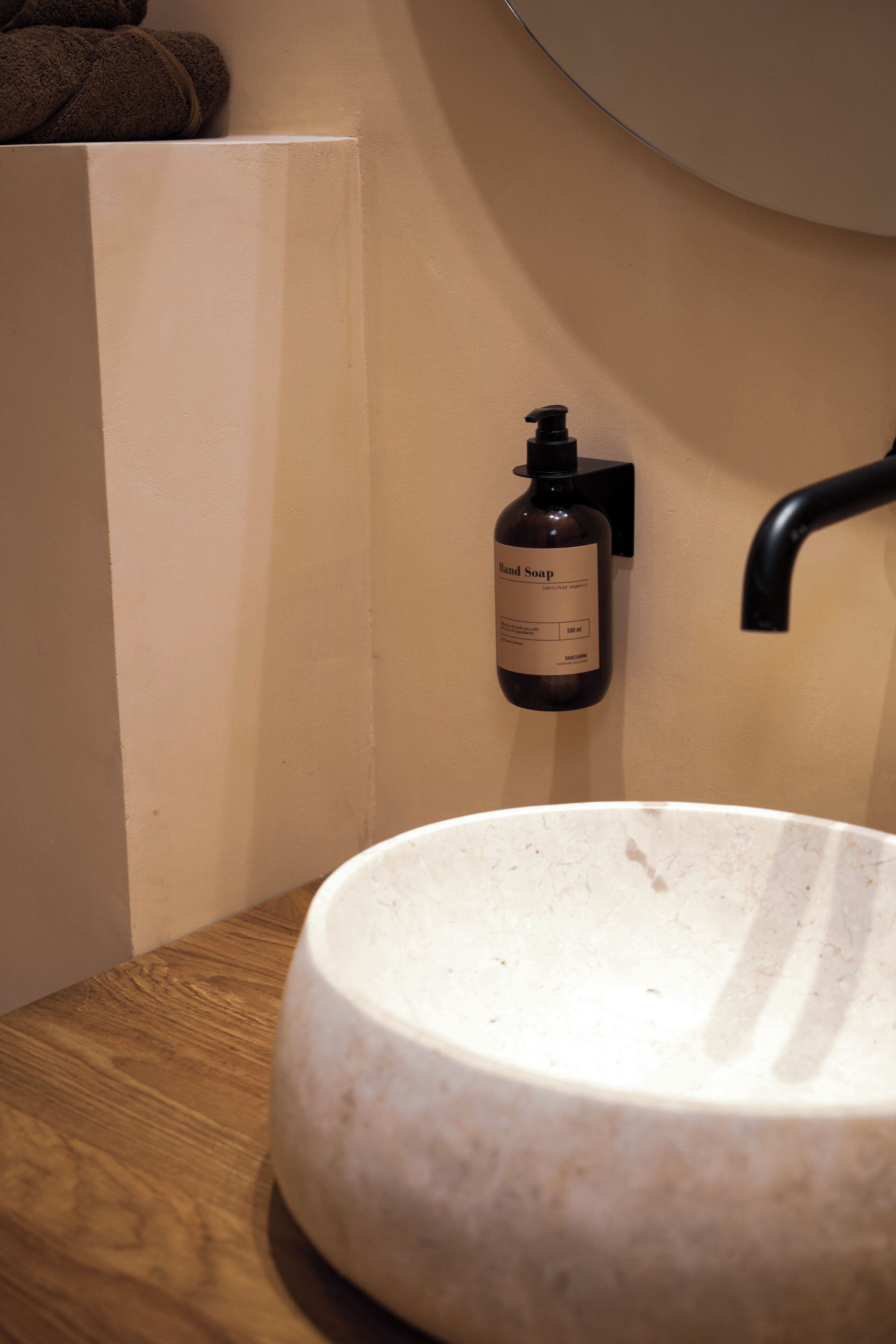 Un baño con un lavabo redondo, una botella de jabón para manos y un perchero para toallas.