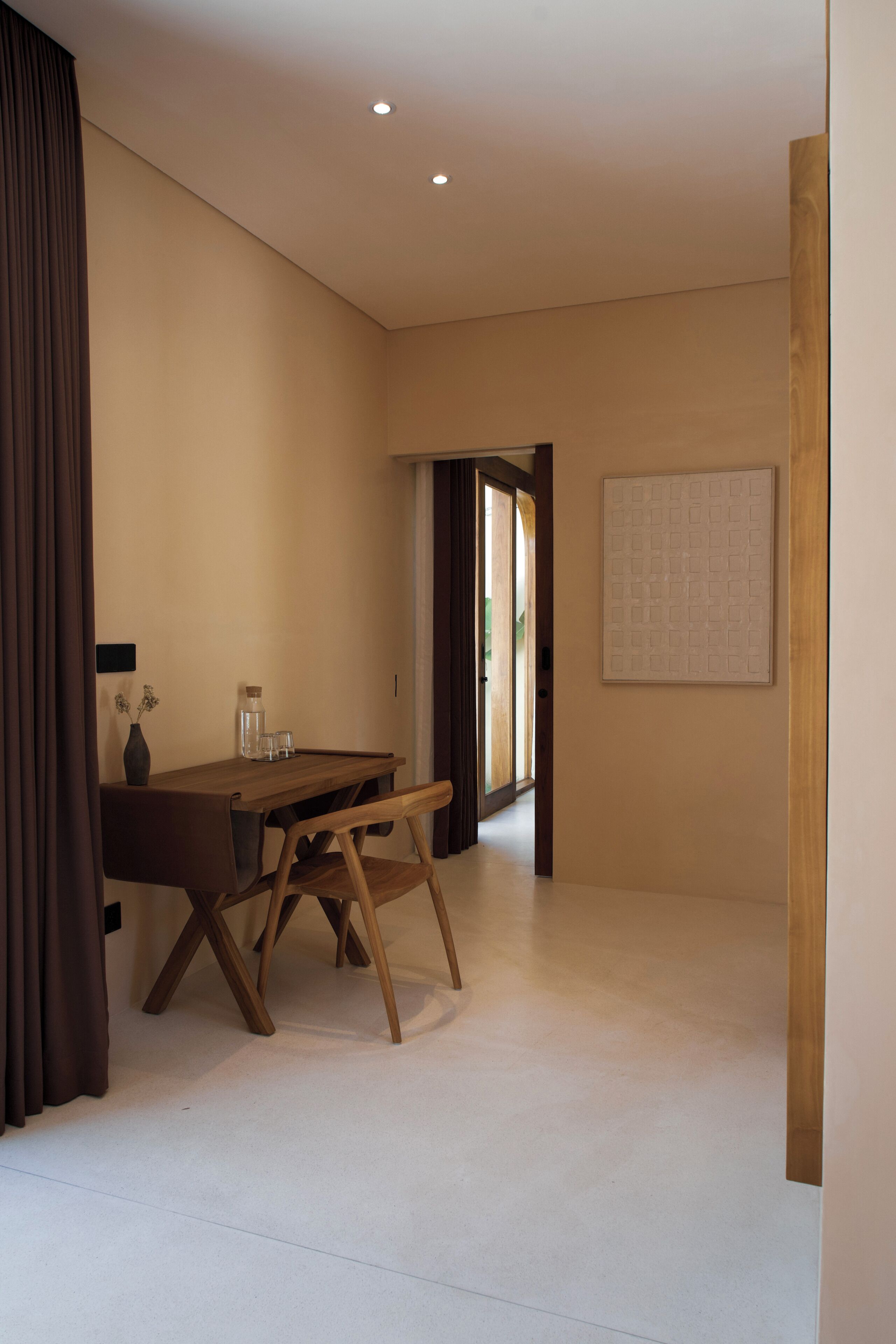 A room with a wooden dining table, chairs, a vase, and a framed picture on the wall.