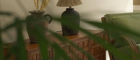 Una habitación con un armario de madera, una lámpara y un florero con plantas secas.