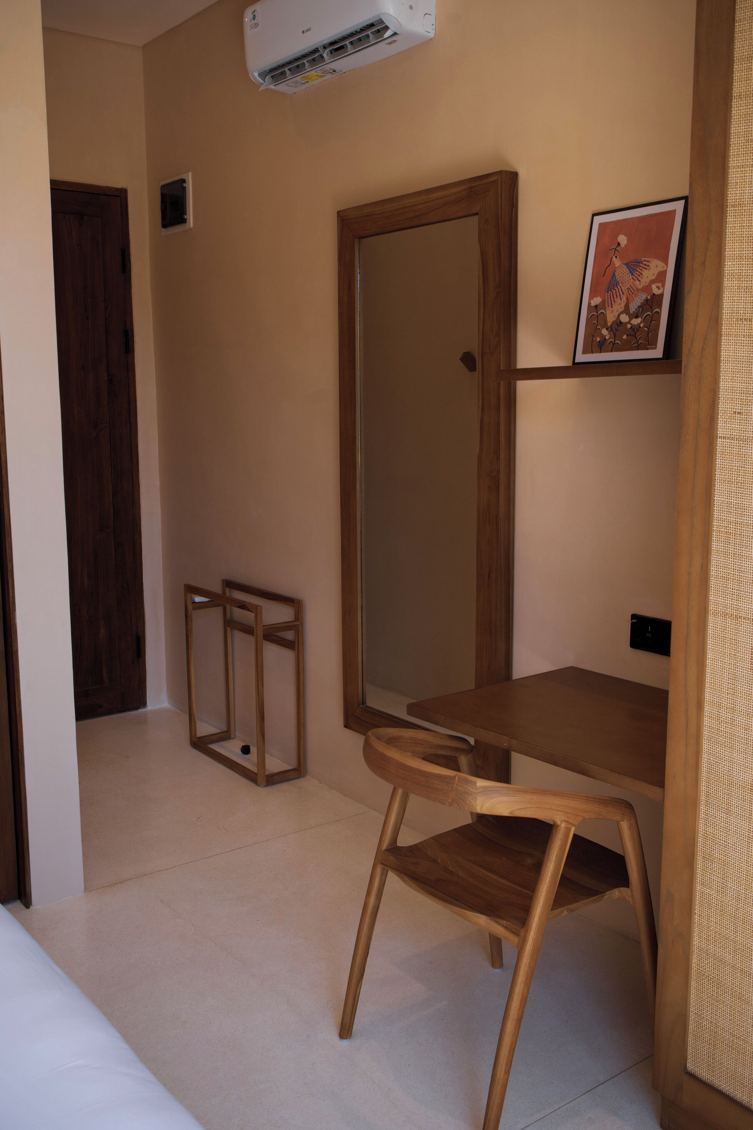 A room with a wooden desk, a chair, a large mirror, and a framed picture on the wall.