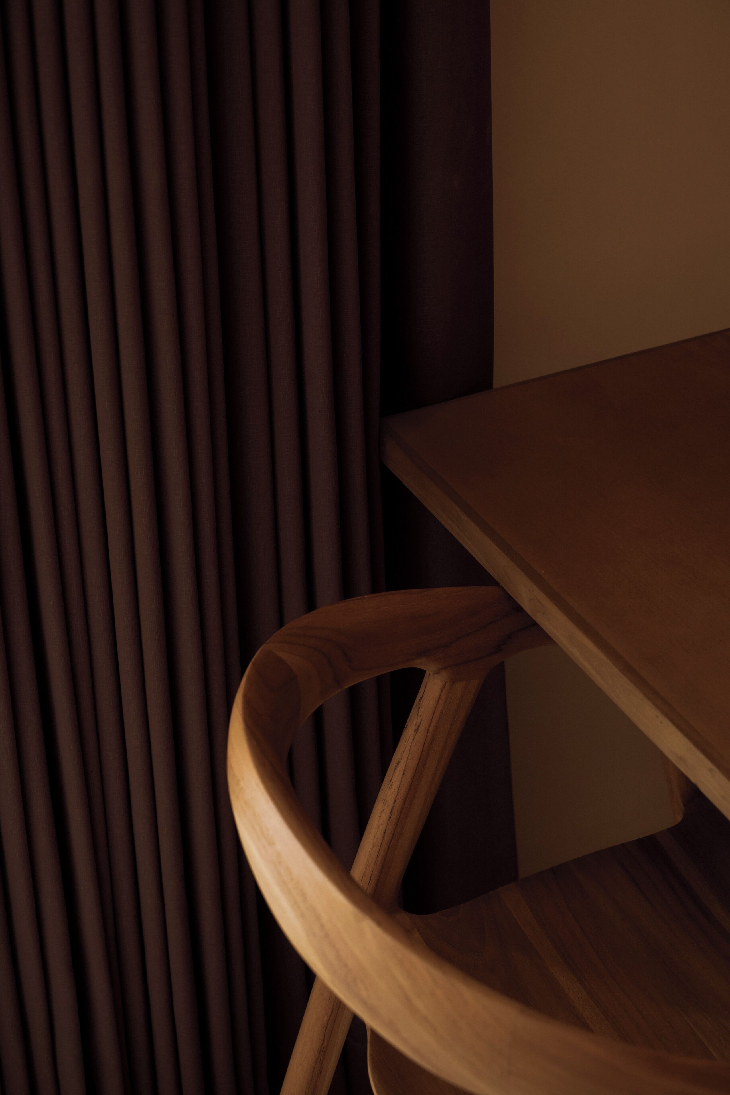 Una silla de madera con respaldo curvo y una mesa de madera.