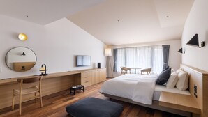 Ein modernes Hotelzimmer mit Bett, Schreibtisch, Stuhl und einer Essecke mit Tisch und Stühlen.