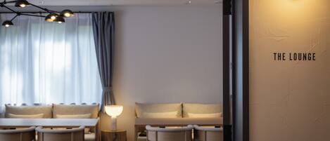 Un salon moderne avec un canapé, des fauteuils, une table et une lampe.