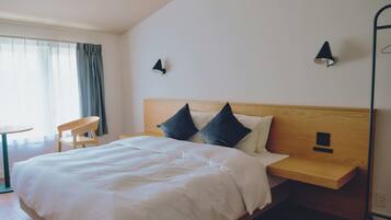 A neatly made bed with white linens, a wooden headboard, and two bedside lamps.