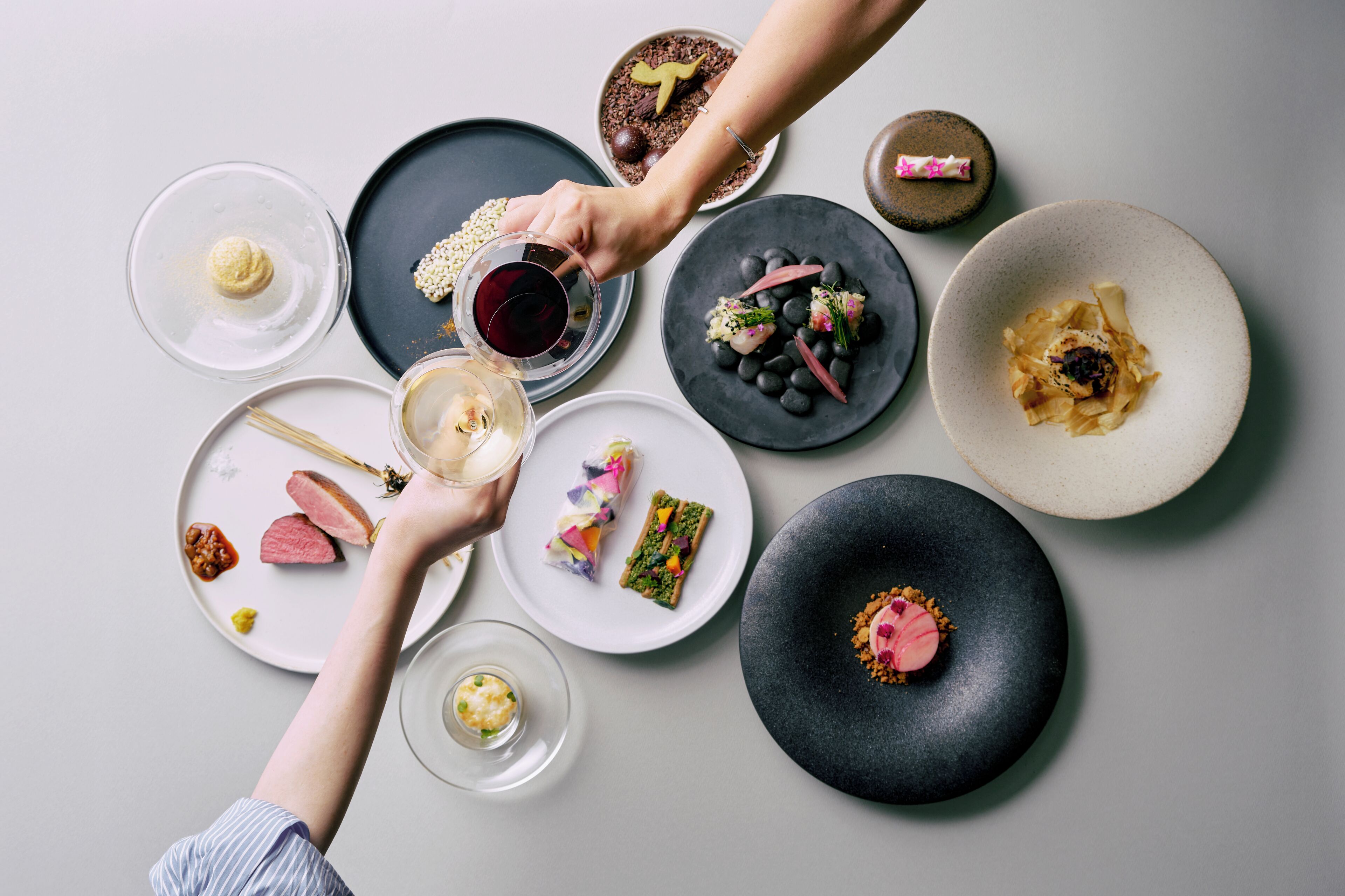A top-down view of a dining table with various dishes and a glass of red wine.
