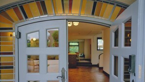 An open door leading to a room with a wooden floor, a brick fireplace, and a view of a garden. - BIRD HOTEL (Kamakura)