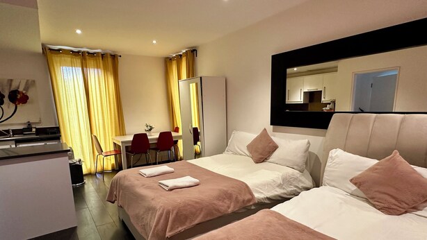 A hotel room with two beds, a desk, and a chair. - Eurostar Comfort Inn Studio Apartments (London)