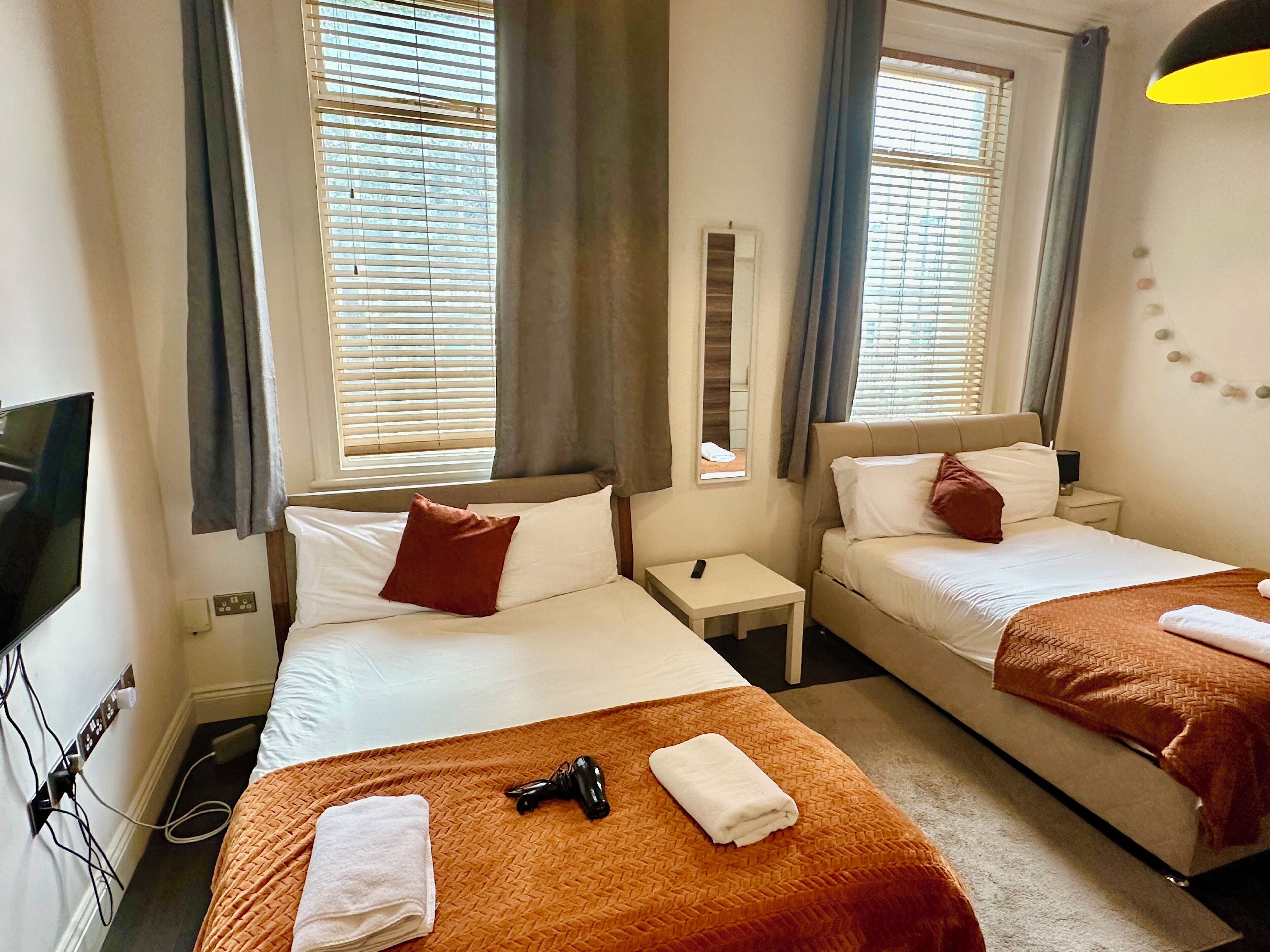 Habitación de hotel con dos camas, televisión y espejo.