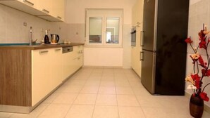 Una cocina moderna con horno empotrado, refrigerador y ventana con persianas.