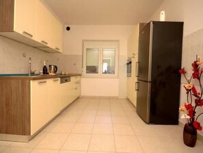 Eine moderne Küche mit Einbauofen, Kühlschrank und einem Fenster mit Jalousien.