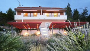 Un edificio de dos pisos con techo rojo, un balcón en el nivel superior y un porche con vigas rojas.