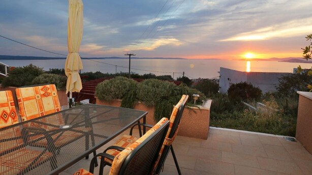 Un patio al aire libre con una mesa y sillas, con vistas a un hermoso atardecer.