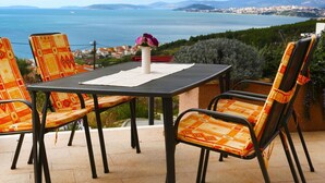 Een terras met een tafel en stoelen, met uitzicht op de kust en bergen in de verte.