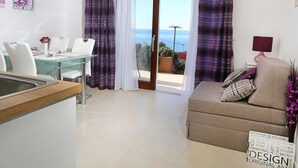Een moderne woonkamer met een glazen eettafel, witte stoelen, een beige bank en paarse gordijnen.