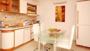 A compact kitchen with white cabinets, a glass dining table, and a microwave. - Strandnahe Ferienwohnung in Podstrana by Interhome (Podstrana)