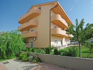 Ein mehrstöckiges Gebäude mit Balkonen, einem gepflasterten Innenhof und umgebender Bepflanzung.