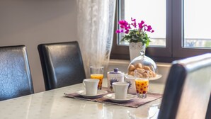 A breakfast setup with a table, chairs, a coffee pot, a glass of orange juice, and a flower vase. - Villa "Petra" mit Blick auf das Wasser by Interhome (Podstrana)
