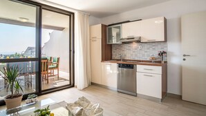 A modern kitchen with a dishwasher, a dining area with a table and chairs, and a view through a sliding glass door. - Villa "Petra" mit Blick auf das Wasser by Interhome (Podstrana)