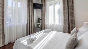 A hotel room with a large bed, white curtains, a flat-screen TV mounted on the wall, and a small table with a vase of flowers. - Villa Meri Split by Interhome (Dragovode)