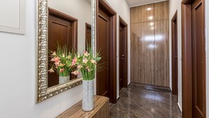 A hallway with a wooden floor, a large mirror, and a wooden console table with a vase of flowers. - Villa Meri Split by Interhome (Dragovode)