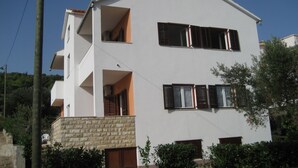 A two-story building with a white facade, multiple windows with shutters, and a stone base. - mit Balkon by Interhome (Trogir/Slatine)