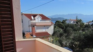A balcony with a round table and four white plastic chairs, overlooking a residential area with houses and mountains in the distance. - mit Balkon by Interhome (Trogir/Slatine)