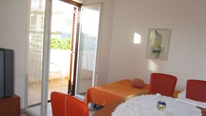 A room with a bed, a table with a white lace tablecloth, and two red chairs. - mit Balkon by Interhome (Trogir/Slatine)