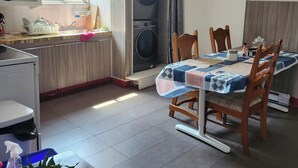 A kitchen with a built-in washing machine, a dining table with chairs, and a potted plant.