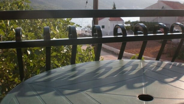 Un balcon avec vue sur des collines et un plan d’eau.
