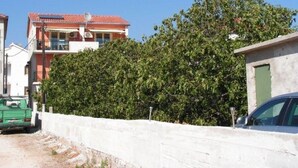 Un quartier résidentiel avec un bâtiment à toit rouge, une voiture verte et un mur blanc.